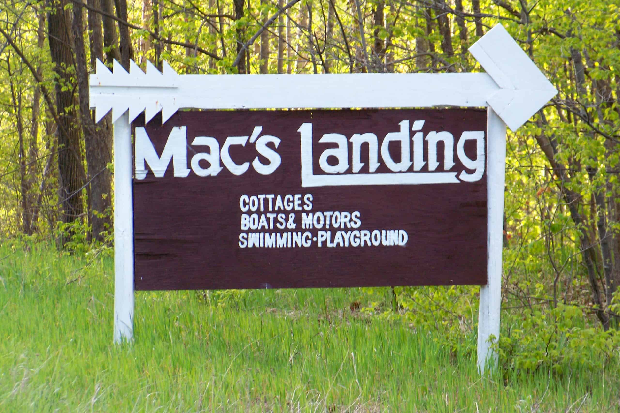 Sign for Mac's Landing with cottages, boats, motors, swimming, and playground.